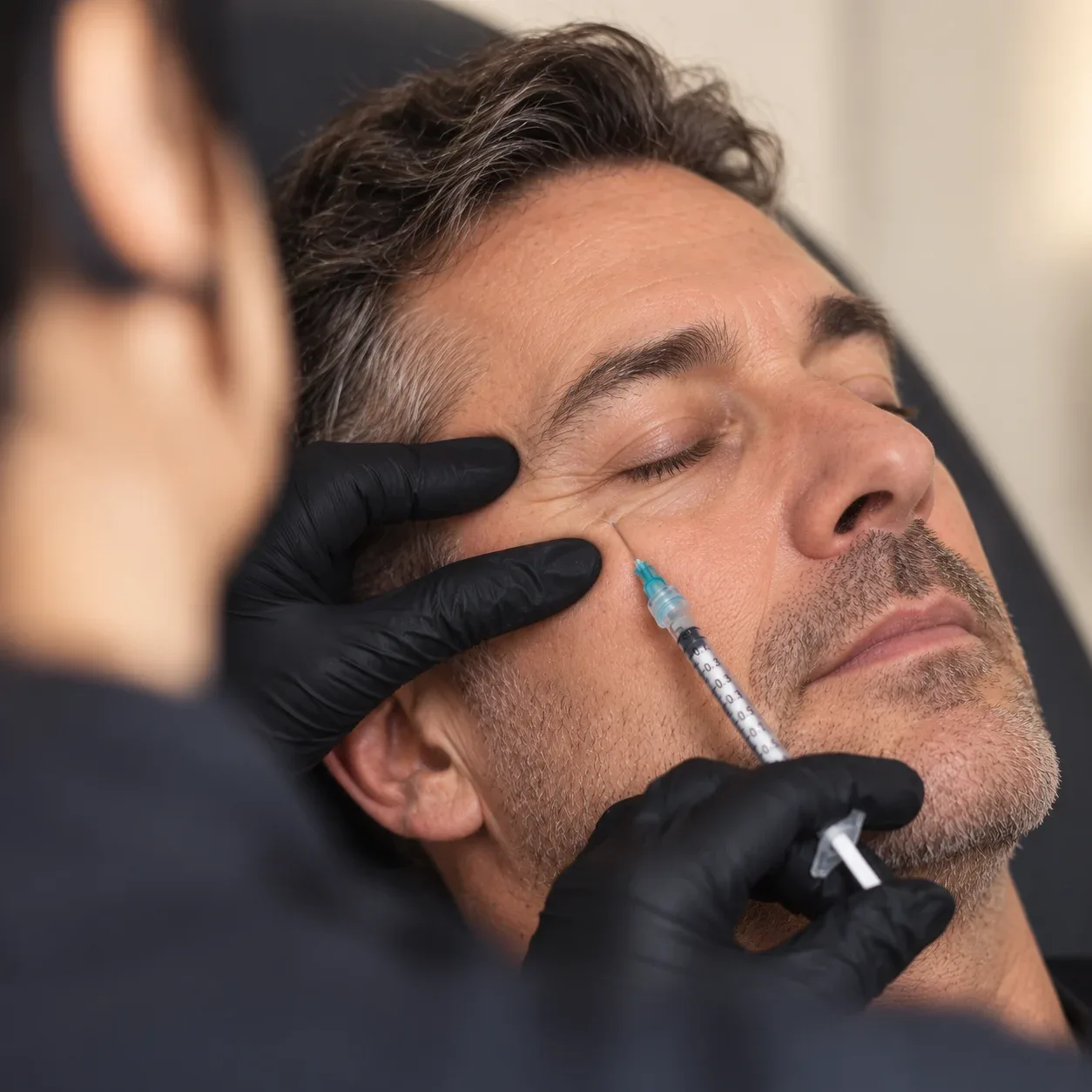 An injection needle is positioned below a reclining man's eye.
